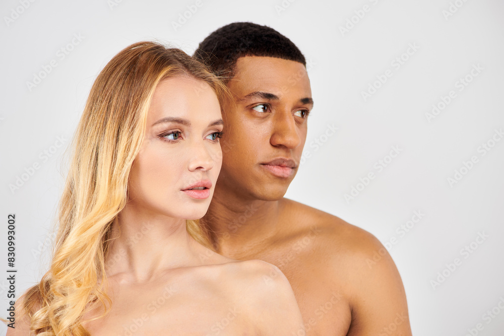 Trendy diverse couple posing elegantly in front of a white backdrop. Trendy diverse couple posing elegantly in front of a white backdrop.