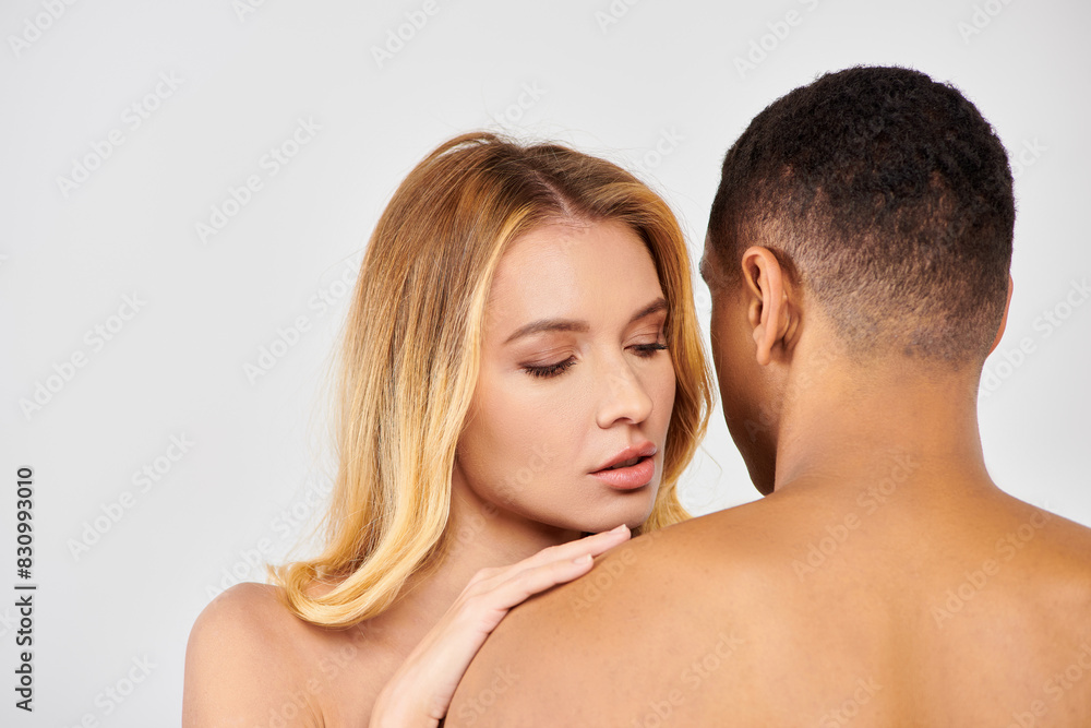 Trendy diverse couple lovingly embrace on white backdrop. Trendy diverse couple lovingly embrace on white backdrop.