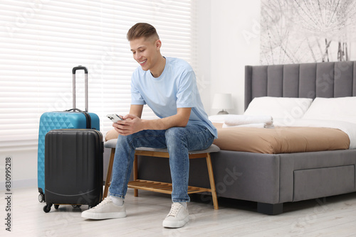 Smiling guest with smartphone and suitcase in stylish hotel room © New Africa