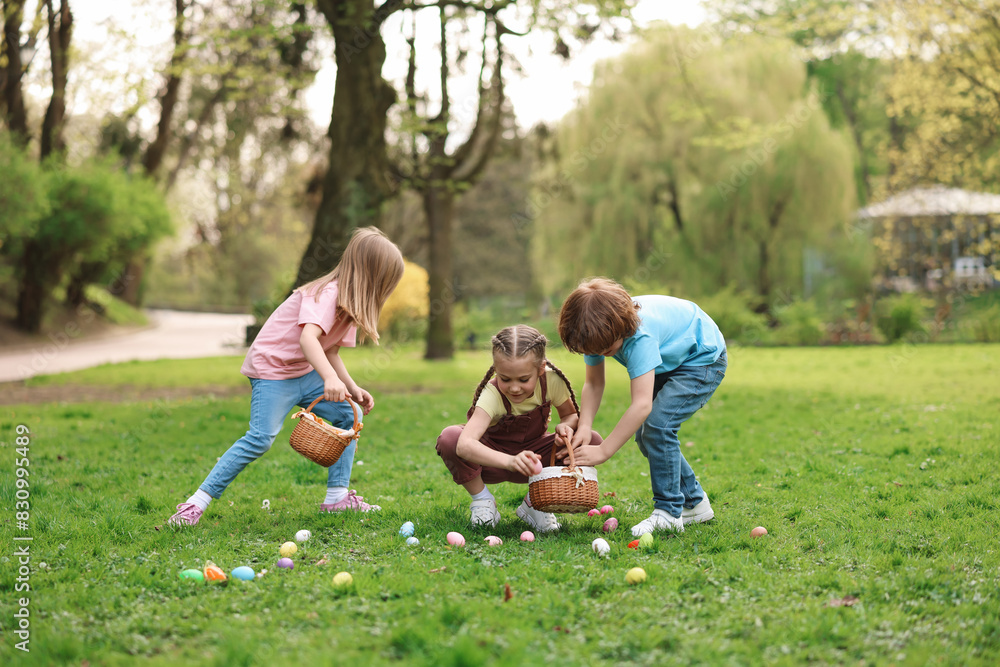 Fototapeta premium Easter celebration. Cute little children hunting eggs outdoors