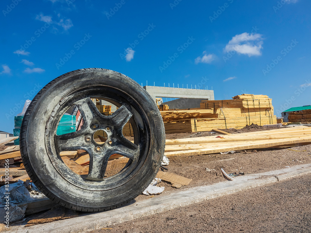 Φωτογραφία Upright old tire by the curb of a new street with a single-family house under co