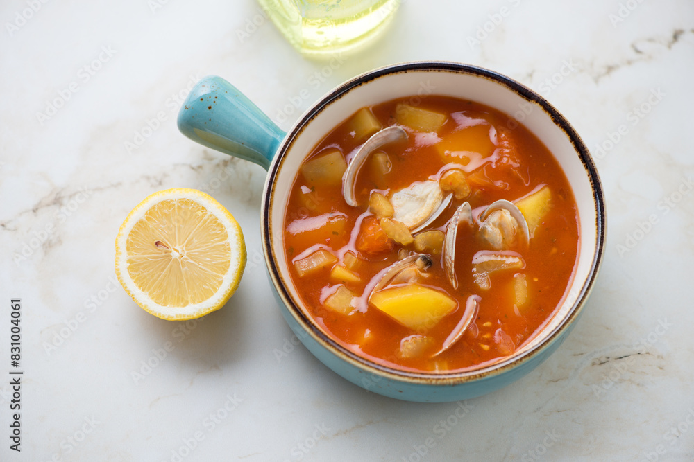 Manhattan clam chowder in a turquoise serving bowl, horizontal shot on a light-beige marble surface, high angle view Manhattan clam chowder in a turquoise serving bowl, horizontal shot on a light-beige marble surface, high angle view