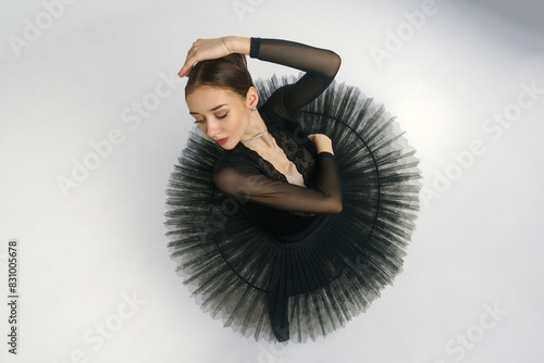 portrait of a young ballerina in a black tutu dancing with her hands moving top view, immersion in dance