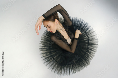 portrait of a young ballerina in a black tutu dancing with her hands moving top view, immersion in dance