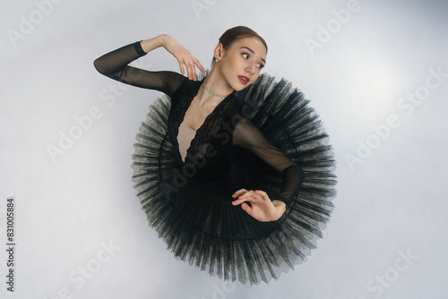 portrait of a young ballerina in a black tutu dancing with her hands moving top view, immersion in dance