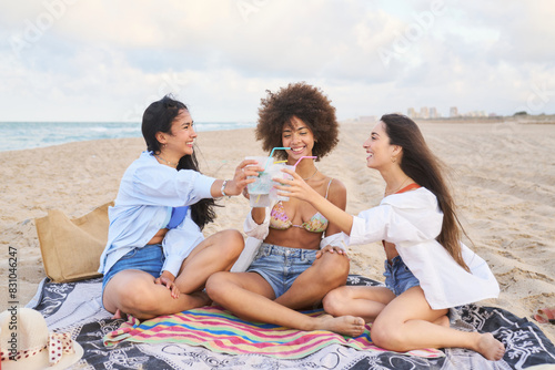 Three women sitting on a blanket on the beach