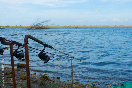 Fishing reels and rods on the edge of the estuary with a cloudy blue sky in the background with copy space. photo