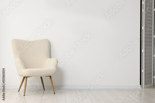 Comfortable armchair near white wall in room, space for text