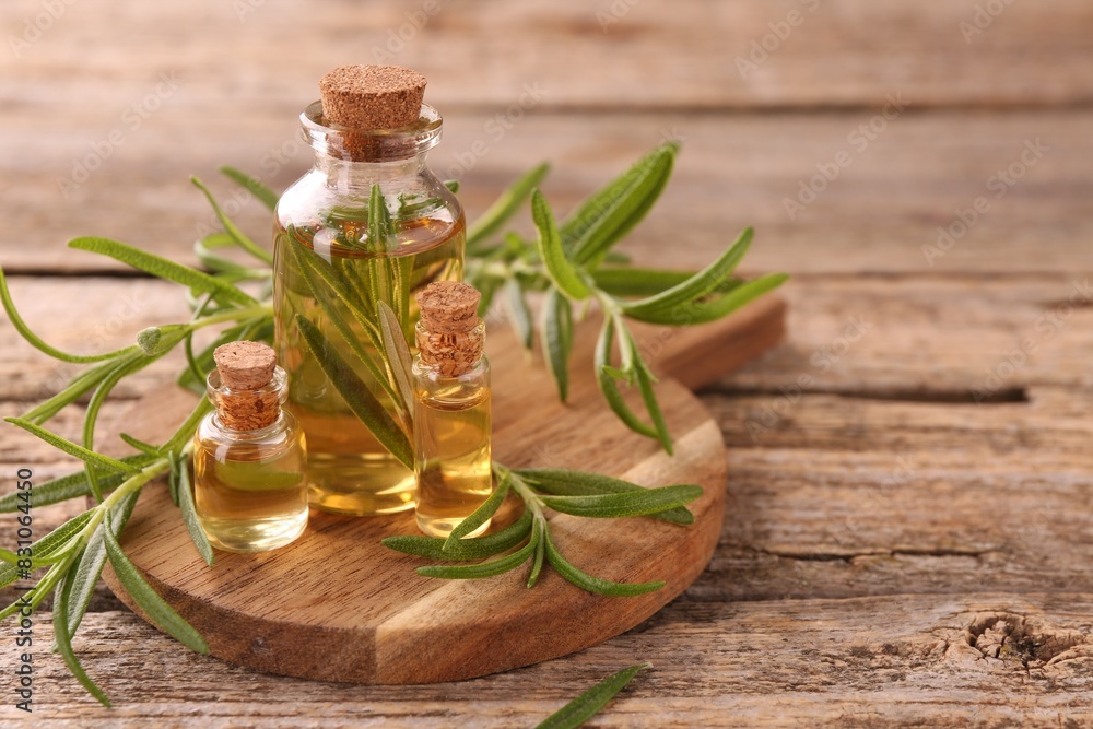 Aromatic essential oils in bottles and rosemary on wooden table, closeup. Space for text Aromatic essential oils in bottles and rosemary on wooden table, closeup. Space for text