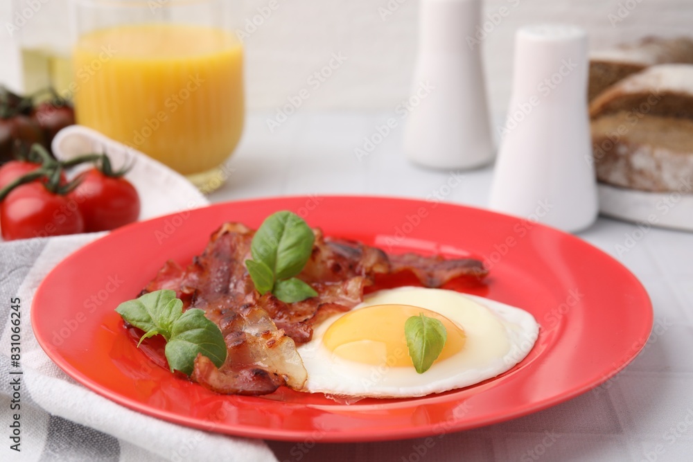 Fried egg, bacon and basil on white table Fried egg, bacon and basil on white table