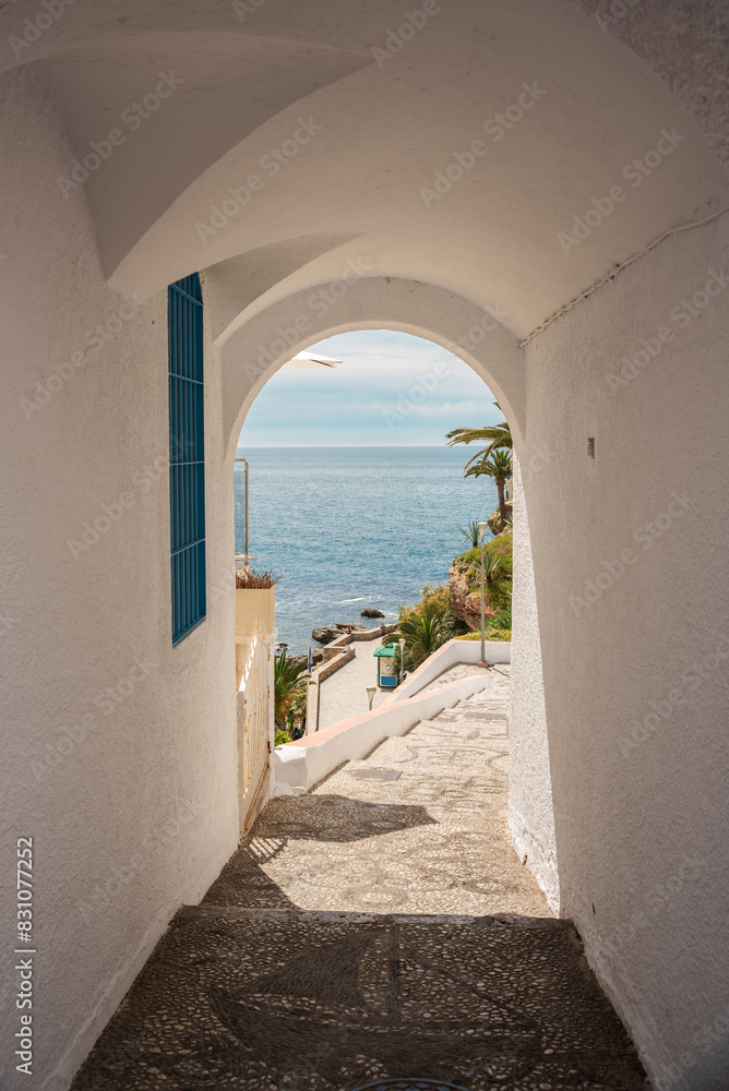 view of the sea from an arched tunnel of a white Andalusian village