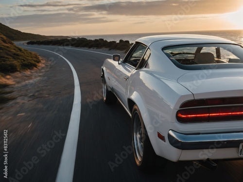 A gleaming white car drives along the coast towards the setting sun.