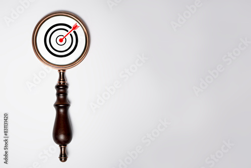 Target board inside of vintage magnifier glass for focus business objective on white background and copy space.