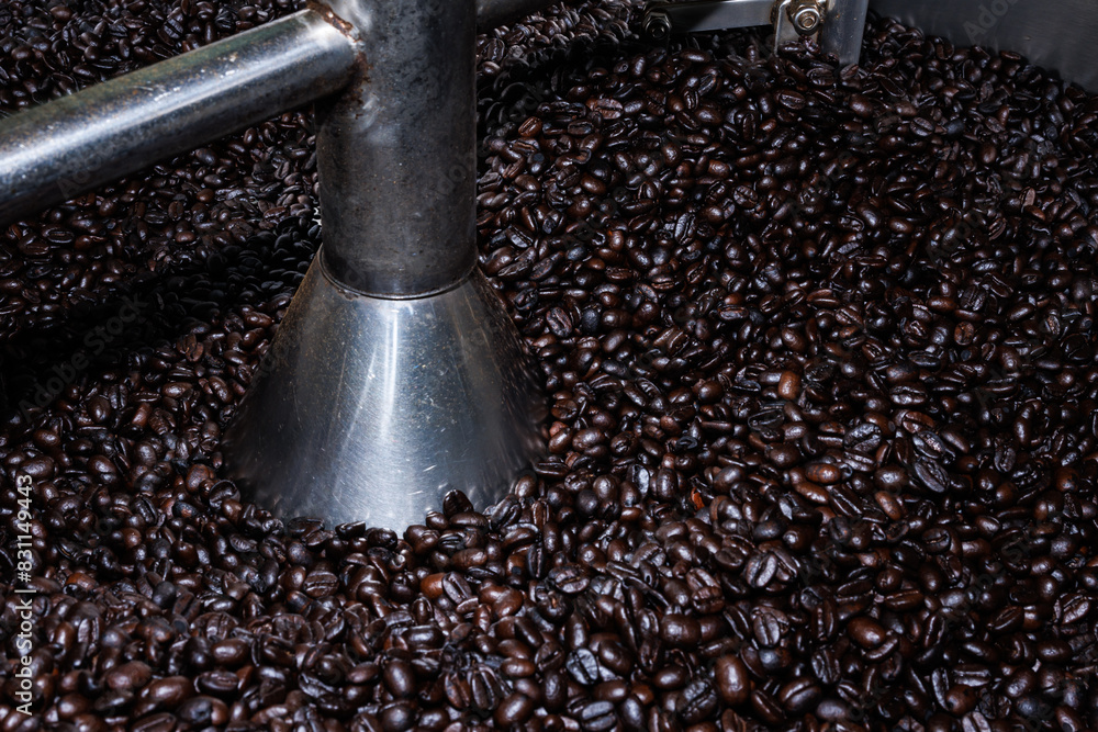 Close up of roasted coffee beans surface rotate in a spinning roaster mashine for background Close up of roasted coffee beans surface rotate in a spinning roaster mashine for background