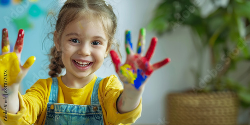 a Caucasian girl gleefully displays her hands adorned with colorful paint  showcasing her creative and imaginative side.