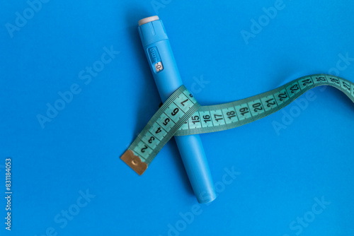 Fotografie Ozempic injector drug with a measuring tape on a blue background
