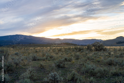 Sunset in the Lamar Valley in Yellowstone National Park in Montana and Wyoming on a beautiful fall evening. Sun sets over the mountains and sagebrush with a colorful sky illuminating the landscape.