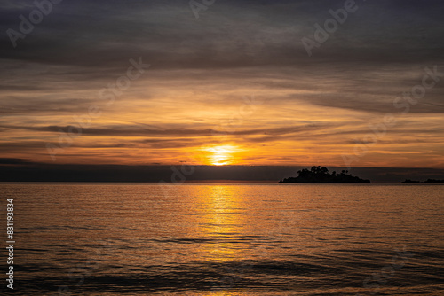 sunset over the sea with bright yellow sun and dark grey clouds, winter near the sea, Montenegro