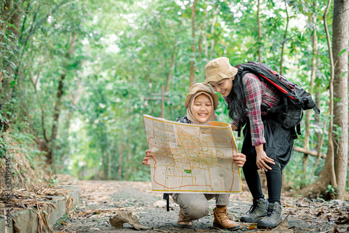 Two beautiful Asian backpacker female looking at the map in the trip road at the forest 