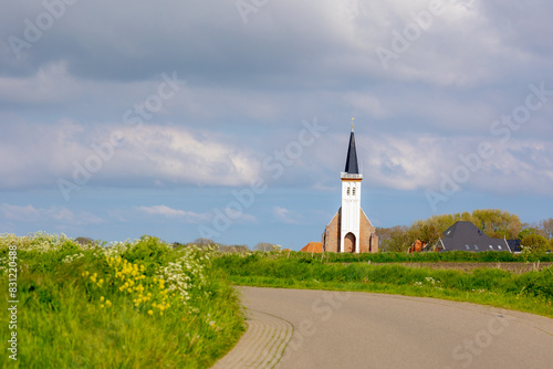 Spring landscape of Texel island, Countryside road with wildflower and green grass, Small village and church (Hervormde kerk) A little town on the wadden islands, Den Hoorn, Noord Holland, Netherlands photo