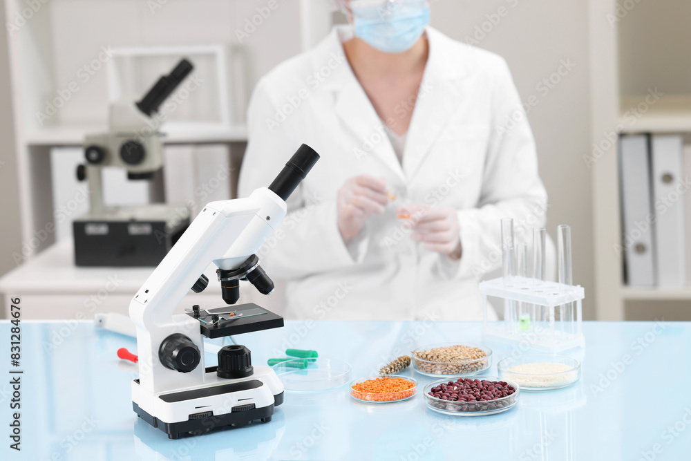 Quality control. Food inspector working in laboratory, focus on microscope and petri dishes with different products Quality control. Food inspector working in laboratory, focus on microscope and petri dishes with different products