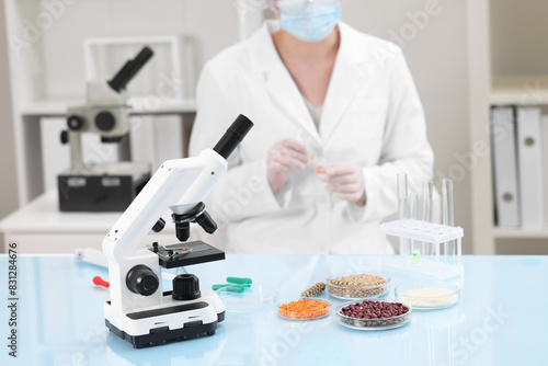 Quality control. Food inspector working in laboratory, focus on microscope and petri dishes with different products