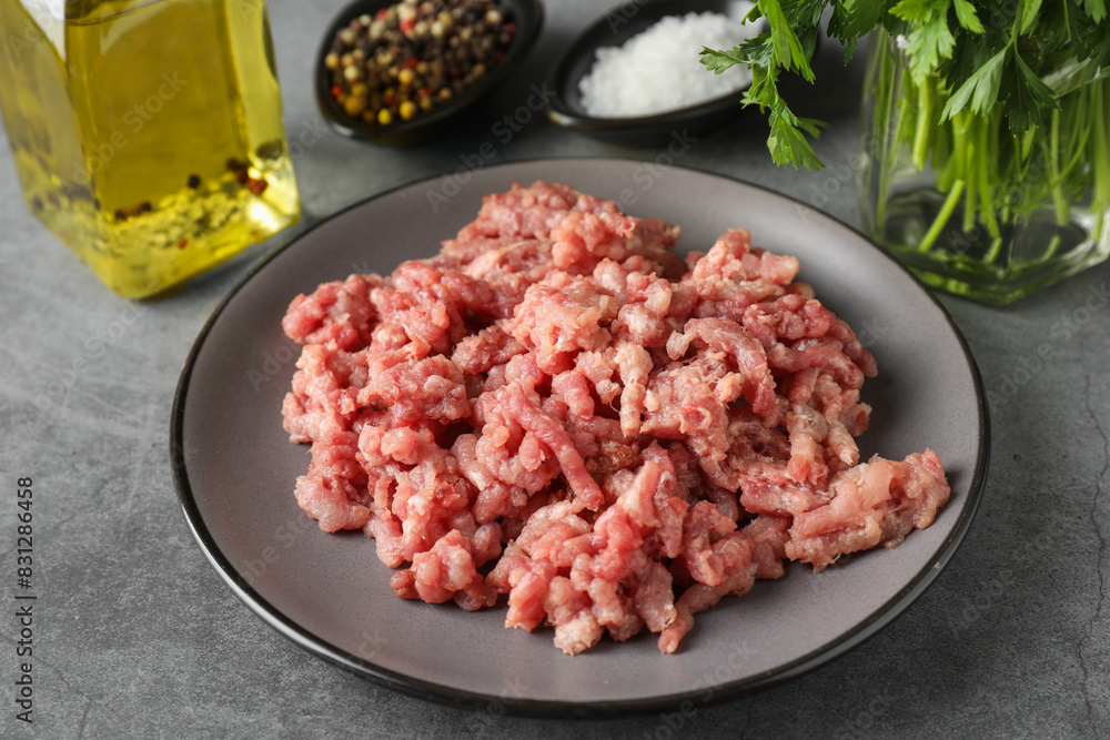 Raw ground meat, spices, parsley and oil on grey table Raw ground meat, spices, parsley and oil on grey table