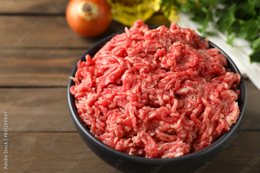Raw ground meat in bowl on wooden table, closeup Raw ground meat in bowl on wooden table, closeup