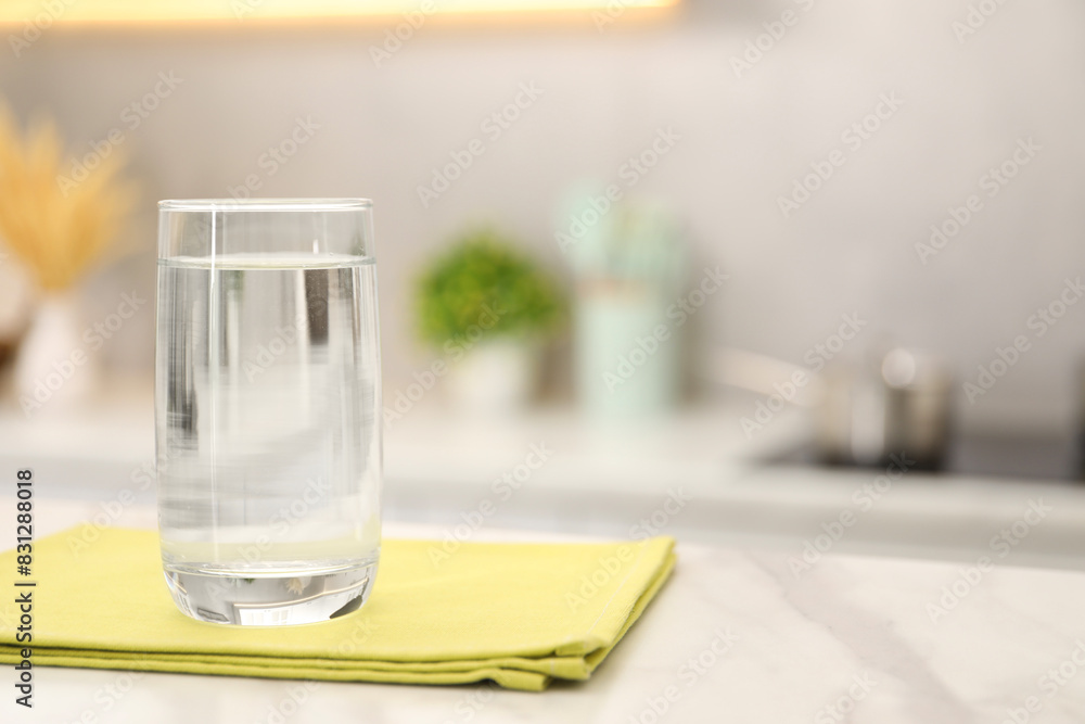 Glass with clear water on white marble table in kitchen, space for text Glass with clear water on white marble table in kitchen, space for text