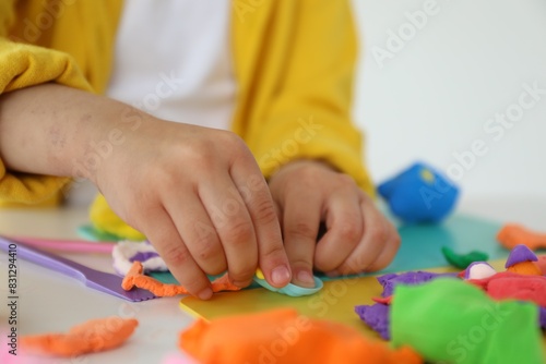 Little girl sculpting with play dough at white table indoors  closeup