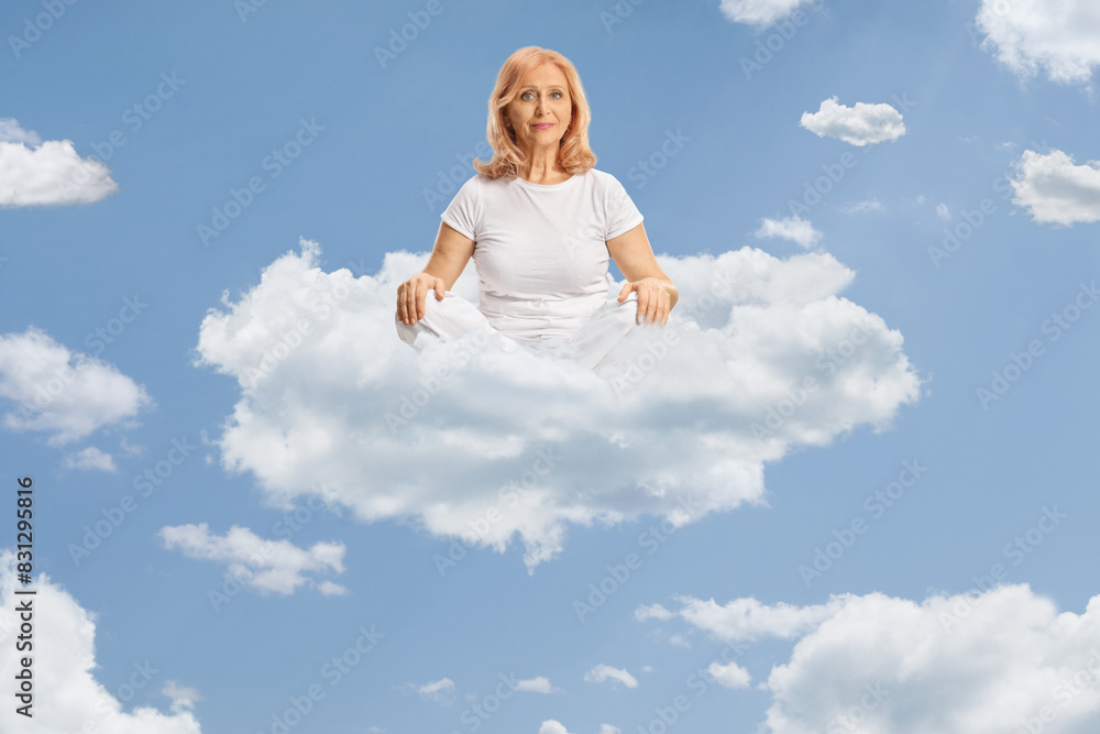 Middle aged woman in white clothes practicing yoga on a cloud Middle aged woman in white clothes practicing yoga on a cloud