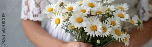 A woman holds a fresh  sunlit bouquet of daisies