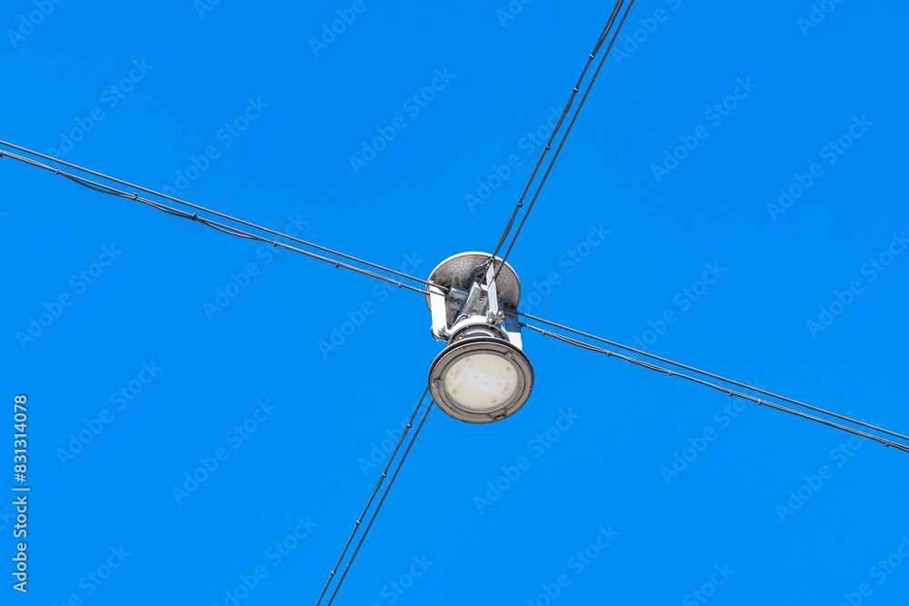 Street lighting lantern suspended on cables against a background of blue sky. Street lighting lantern suspended on cables against a background of blue sky.