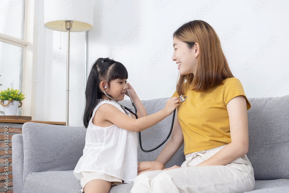 Asian daughter play as a doctor checking up her mother in the living room Asian daughter play as a doctor checking up her mother in the living room