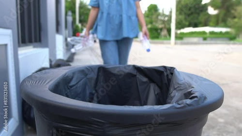 A woman walks through a city park collecting plastic waste for recycling, her hands busy separating trash into eco-friendly bins as part of her mission to save land and sea and fight climate change photo