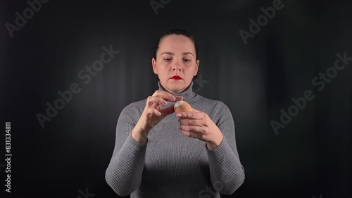 Captivating portrait a beautiful young woman wearing a grey sweater isolated on a sleek black backdrop, peels an egg, eat the meal, exuding an effortless cool vibe. Lifestyle, fashion or culinary