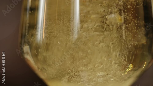Cropped sophisticated champagne glass getting filled with carbonated golden drink with splashing air bubbles. Unknown person pouring sparkling wine for welcoming guests for festive reception.
