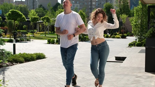 guy and a girl walk funny arm in arm and look at the camera, pose, smile, make eyes, a couple walks along the street. Falling in love sexuality adults young people photo