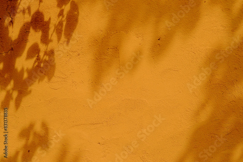 Tree leaves shadow on orange color concrete wall texture background
