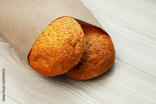 burger buns in a package on a wooden background. appetizing buns with sesame in a paper package	