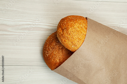 burger buns in a package on a wooden background. appetizing buns with sesame in a paper package	
