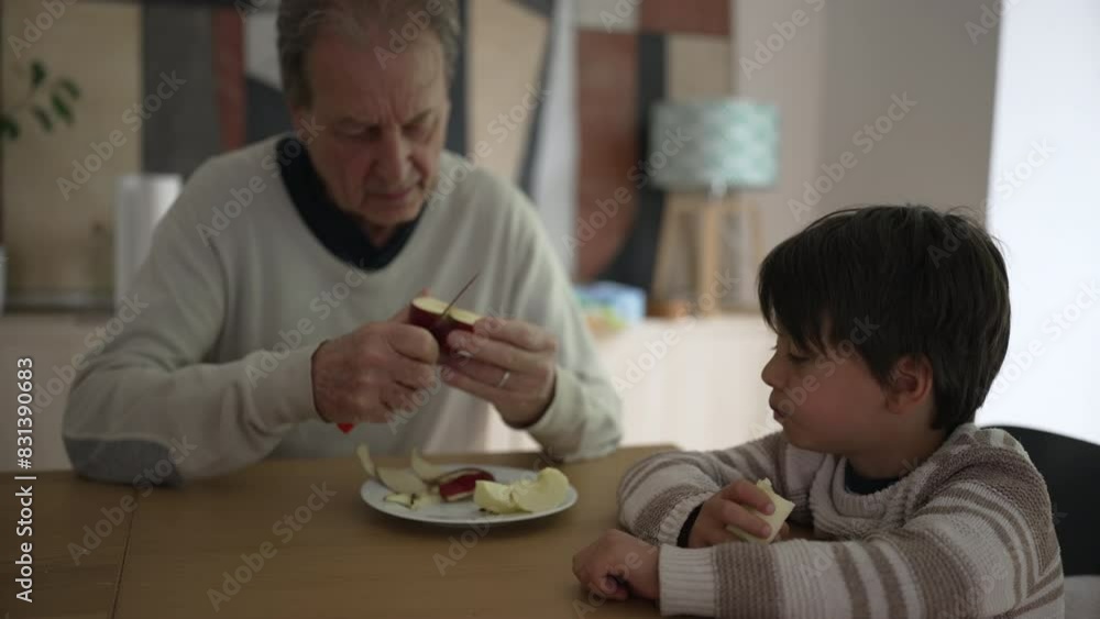 Grandfather peeling and slicing a red apple while his young grandson watches attentively, capturing a moment of teaching and bonding over a healthy snack in a warm home setting Grandfather peeling and slicing a red apple while his young grandson watches attentively, capturing a moment of teaching and bonding over a healthy snack in a warm home setting