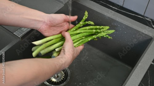 Close up of Woman Hands Washing Asparagus in the Kitchen Sink. Washing vegetables by hand before cooking.