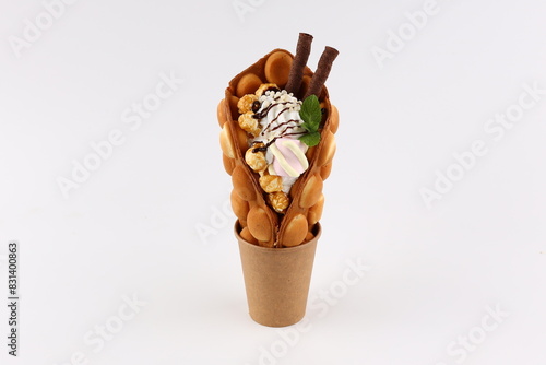 Trendy Hong Kong bubble waffles with ice cream, cream and berries on white wooden background. Copy space