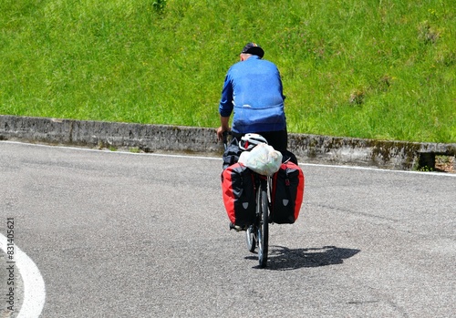 Canvas Print Cyclist with panniers on a bikepacking trip on an uphill mountain road in summer