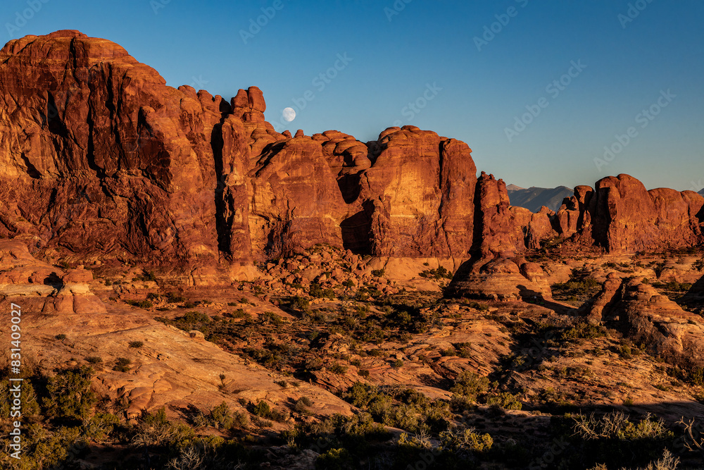 Panorama au coucher du soleil de Arches National Park, Utah, USA, avec la lune dans le ciel bleu au dessus des roches rouges. Panorama au coucher du soleil de Arches National Park, Utah, USA, avec la lune dans le ciel bleu au dessus des roches rouges.