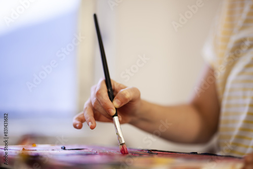 Hand using brush on an artistic painting. Female artist creating art.