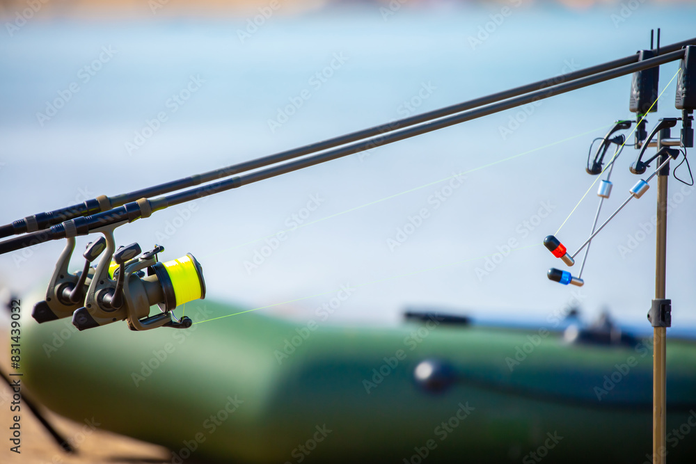 Close-up of fishing rod reels. Fishing on the shore of the lake. Spinning rods for sport fishing. Close-up of fishing rod reels. Fishing on the shore of the lake. Spinning rods for sport fishing.