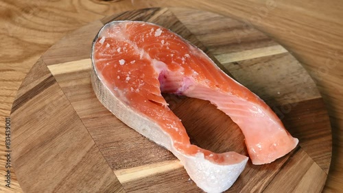 Woman hands salting fresh raw salmon steak before baking
