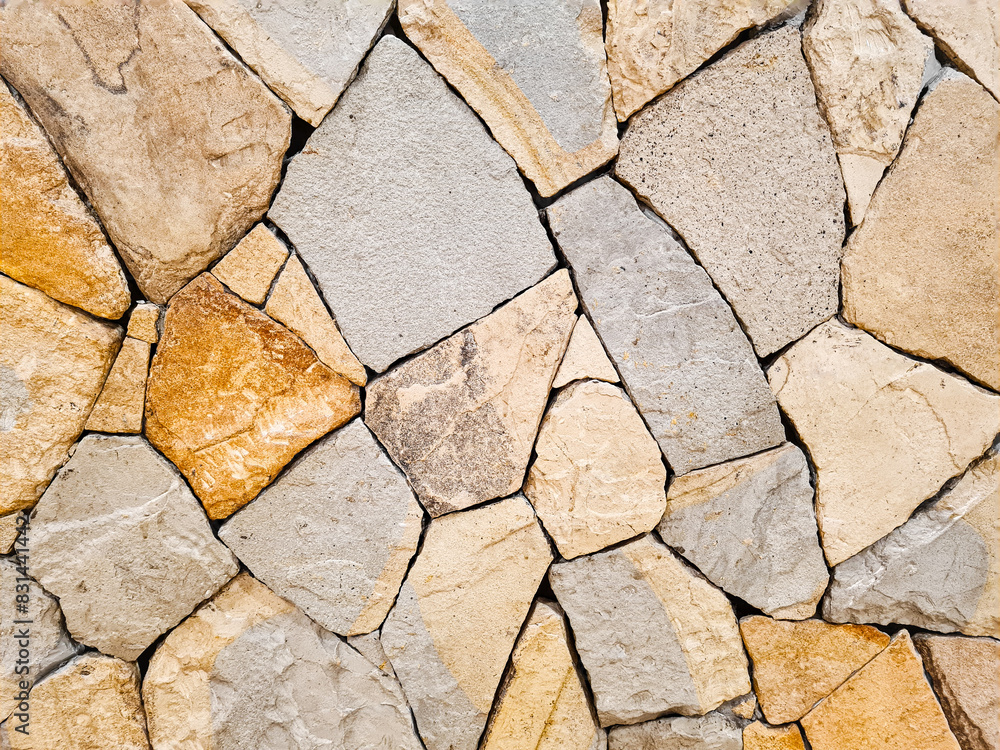 Fototapeta premium Background of a beige and gray Fieldstone mosaic wall. Old stone wall texture. Abstract stone pattern, home decoration.